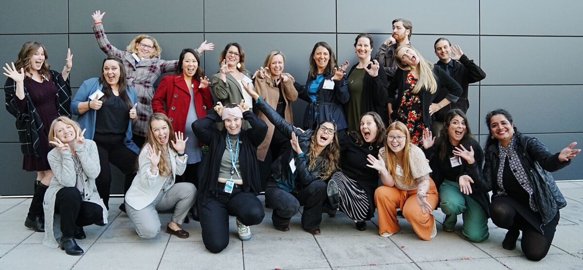 A group of people making silly faces and gestures. Some people are standing, and others are kneeling.